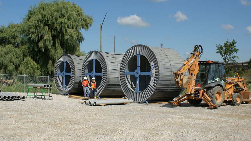 WIR employees working at a construction site with cable spools in the background